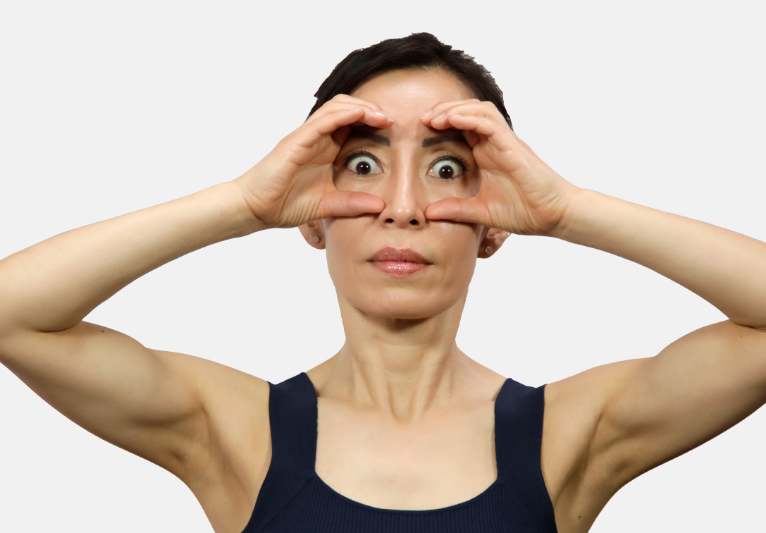 Woman doing face yoga exercises for eyes and forehead