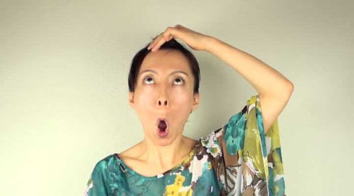 Fumiko Takatsu doing a face yoga exercise for eye bags while holding her mouth in big O shape.