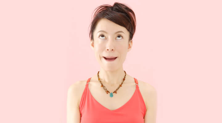 A woman in red sleeveless shirt looking up and and making expression with her mouth