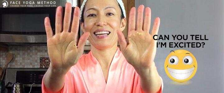 Fumiko Takatsu with a shower cap and in a pink bathrobe, smiling towards the camera while showing both of her palms.
